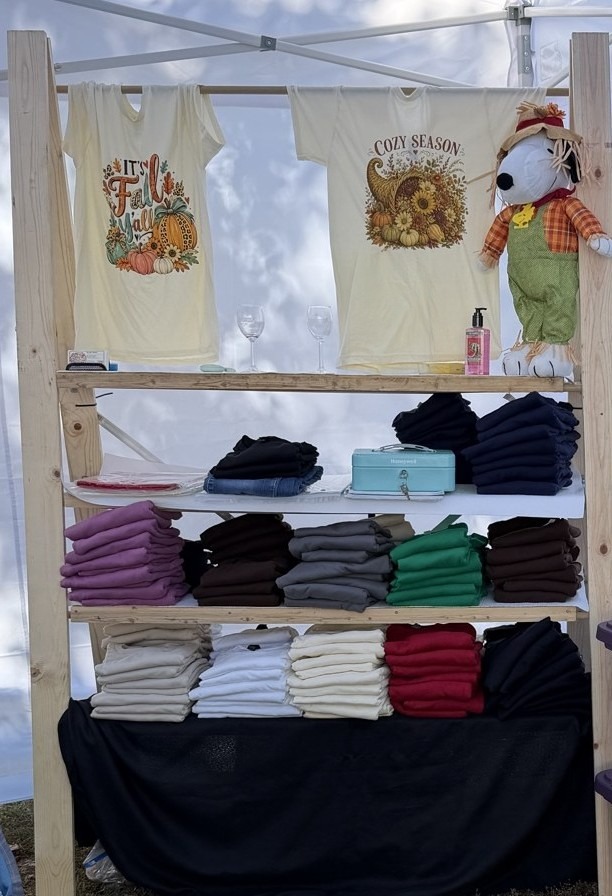 Betty Ellen's wooden rack with fall tees hanging and folded shirts on the shelves