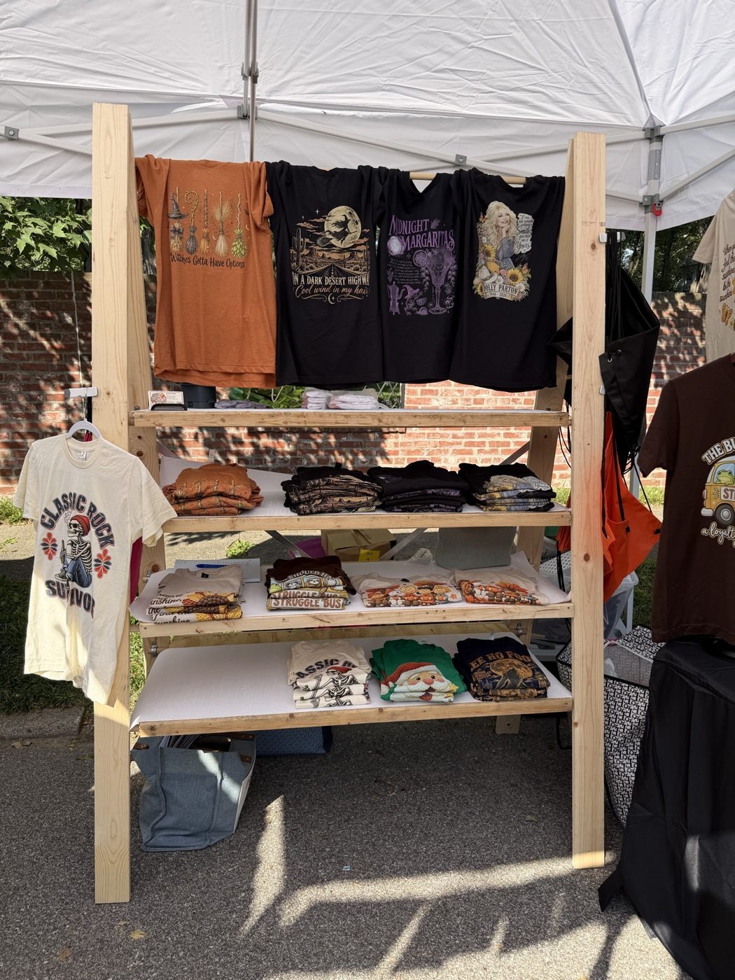 Tees hanging and folded on a wooden shelf